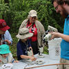 Kids and adult engaging in citizen science by looking at samples through microscopes.
