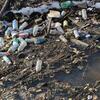 trash floating in a body of water. specifically plastic bottles
