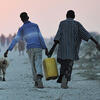 Two men carrying a pail of water